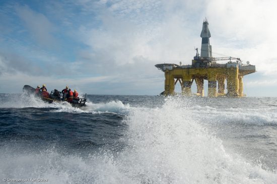 Two swimmers backed by 2 rhibs launched from the Greenpeace ship MY Esperanza jump in the Pacific Ocean in front of Shells subcontracted drilling rig, the Polar Pioneer, holding a floating banner that reads People Vs Oil. Meanwhile, the radio operator from the MY Esperanza warns the Polar Pioneer that swimmers are floating ahead of them, communicates the nature of the protest and requests that they slow down or change course.