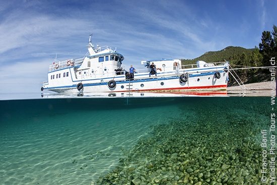 Valeria liveaboard, diving boat, anchored in front of the coast, in clear water on Lake Baikal, Siberia, Russia