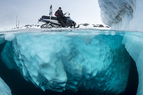 Split image of guide with snowmobile waiting the divers, only in springtime, when the hard winter slowly subsides, are the ice-cold waters suitable for divers who can dive around a iceberg that floats in crystal-clear water, Tasiilaq, East Greenland