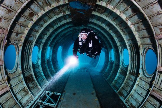 A diver (Caroline Robertson-Brown) explores inside a wreck of a plane, purposely sunk in a freshwater lake. The plane is a Hawker Siddeley (HS) 748. Capernwray Quarry, Lancashire, England, British Isles.
