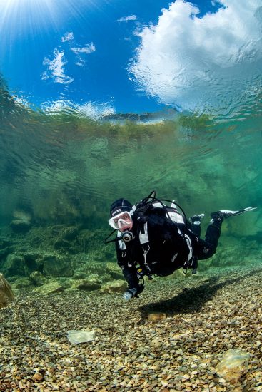 A diver (Caroline Robertson-Brown) explores the shallows of a freshwater lake in England. Capernwray Quarry, Lancashire, England, United Kingdom. British Isles.