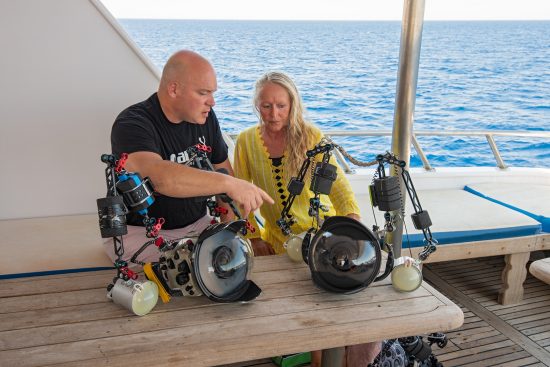 Alex Mustard and Valerie Reid discussing underwater cameras on a diving liveaboard. Sinai, Egypt. Red Sea.