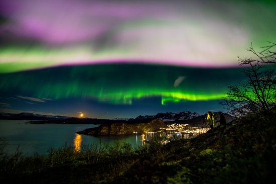 A rare purple streak of northern Lights (Aurora Borealis) in the sky over the sea and town. Skjervoy, Troms, Norway. Arctic Circle. Barents Sea, Arctic Ocean.