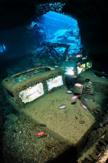 A pair of Fordson WOT 3 trucks (illuminated by off-camera strobes), srrounded by Red Sea soldierfish (Myripristis murdjan) on the lower level of Hold 2 of the wreck of the SS Thistlegorm. Sha'ab Ali, Red Sea. Sinai, Egypt.